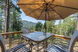 Enjoy breathtaking mountain views from this charming deck, complete with a glass-top table and comfortable seating under a large umbrella.