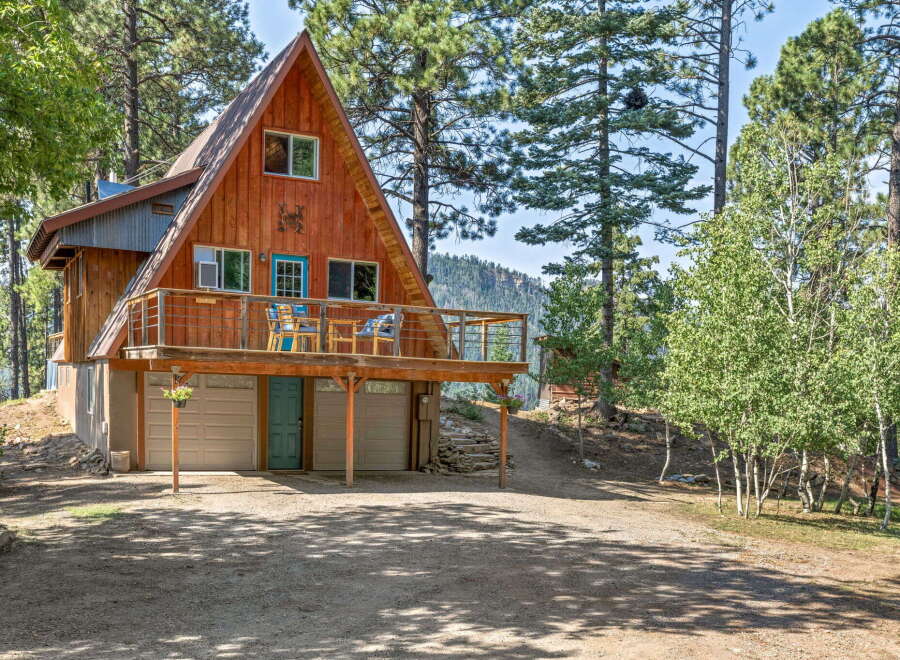 Discover this charming A-frame cabin nestled among tall pine trees, offering a serene mountain retreat.