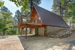 Discover this unique A-frame cabin nestled amongst tall pine trees, featuring a spacious wooden deck perfect for enjoying the serene surroundings.
