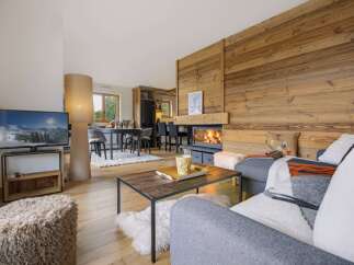 Experience cozy mountain living in this charming living room, featuring a stunning wood-paneled wall and a crackling fireplace.