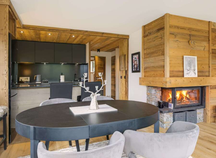 Experience luxury mountain living in this stunning chalet featuring a modern kitchen and a cozy living area with a roaring fireplace.