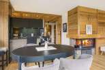 Experience luxury mountain living in this stunning chalet featuring a modern kitchen and a cozy living area with a roaring fireplace.
