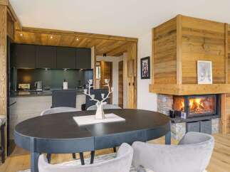 Experience luxury mountain living in this stunning chalet featuring a modern kitchen and a cozy living area with a roaring fireplace.