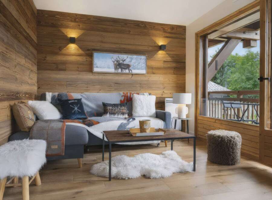 Experience cozy mountain living in this charming living room featuring rustic wood-paneled walls and a comfortable sofa adorned with decorative pillows and throws.
