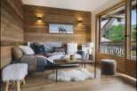 Experience cozy mountain living in this charming living room featuring rustic wood-paneled walls and a comfortable sofa adorned with decorative pillows and throws.