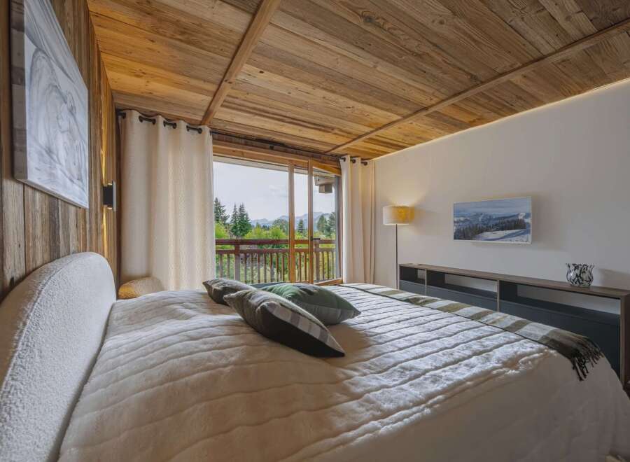 Experience ultimate comfort in this luxurious bedroom, featuring a plush bed and stunning mountain views from the private balcony.