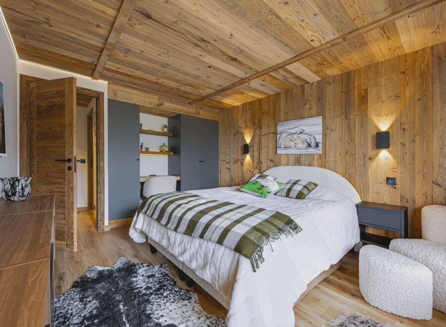 Experience rustic charm and modern comfort in this beautifully appointed bedroom, featuring warm wood paneling on the walls and ceiling.