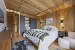 Experience rustic charm and modern comfort in this beautifully appointed bedroom, featuring warm wood paneling on the walls and ceiling.