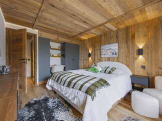 Experience rustic charm and modern comfort in this beautifully appointed bedroom, featuring warm wood paneling on the walls and ceiling.
