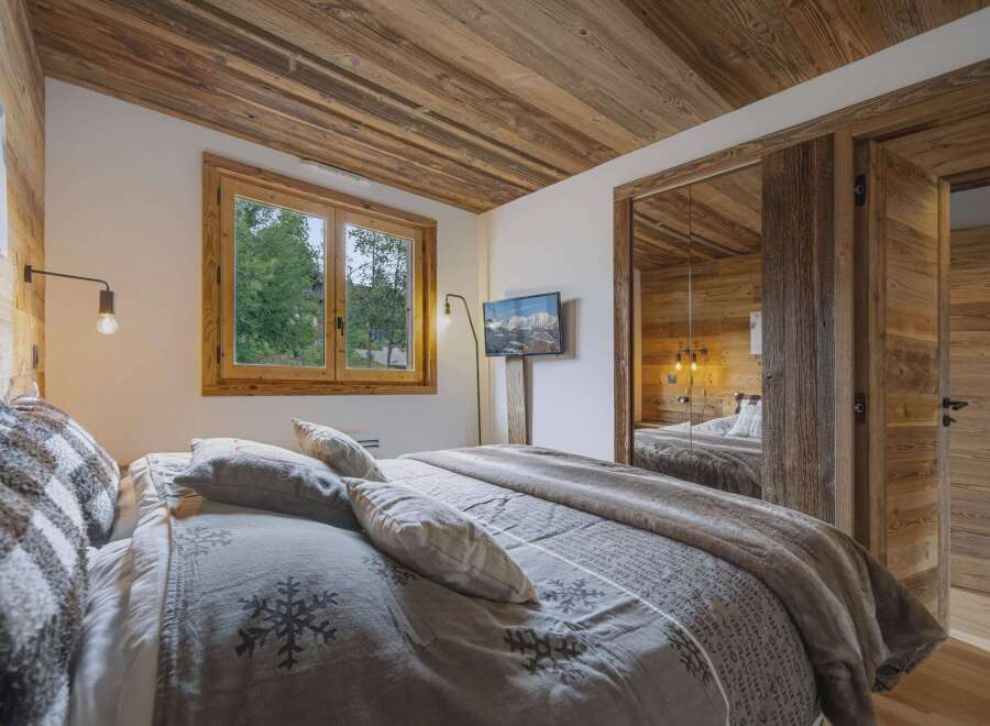 Experience rustic charm in this beautifully appointed bedroom, featuring a cozy bed adorned with snowflake-patterned linens and plush throws.