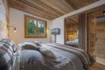 Experience rustic charm in this beautifully appointed bedroom, featuring a cozy bed adorned with snowflake-patterned linens and plush throws.