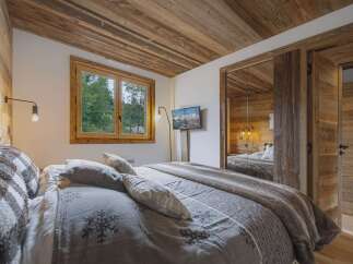 Experience rustic charm in this beautifully appointed bedroom, featuring a cozy bed adorned with snowflake-patterned linens and plush throws.