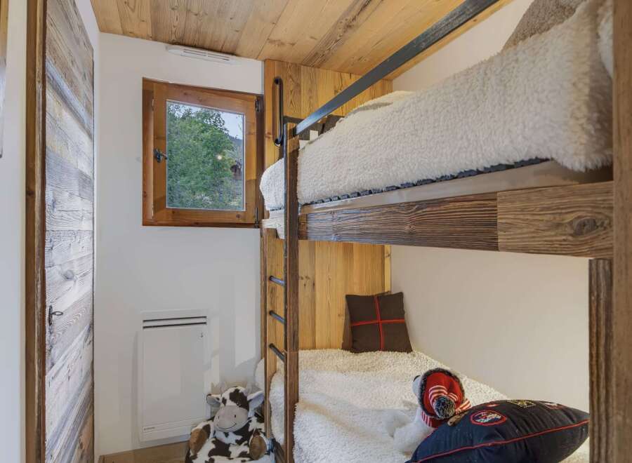 This charming room features cozy bunk beds with plush white bedding, perfect for a family or guests.