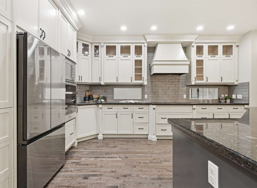 Experience luxury in this stunning kitchen, featuring sleek white custom cabinetry and a spacious granite island perfect for entertaining.