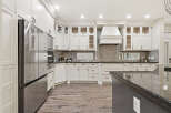 Experience luxury in this stunning kitchen, featuring sleek white custom cabinetry and a spacious granite island perfect for entertaining.