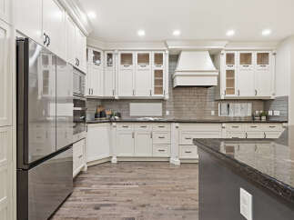 Experience luxury in this stunning kitchen, featuring sleek white custom cabinetry and a spacious granite island perfect for entertaining.