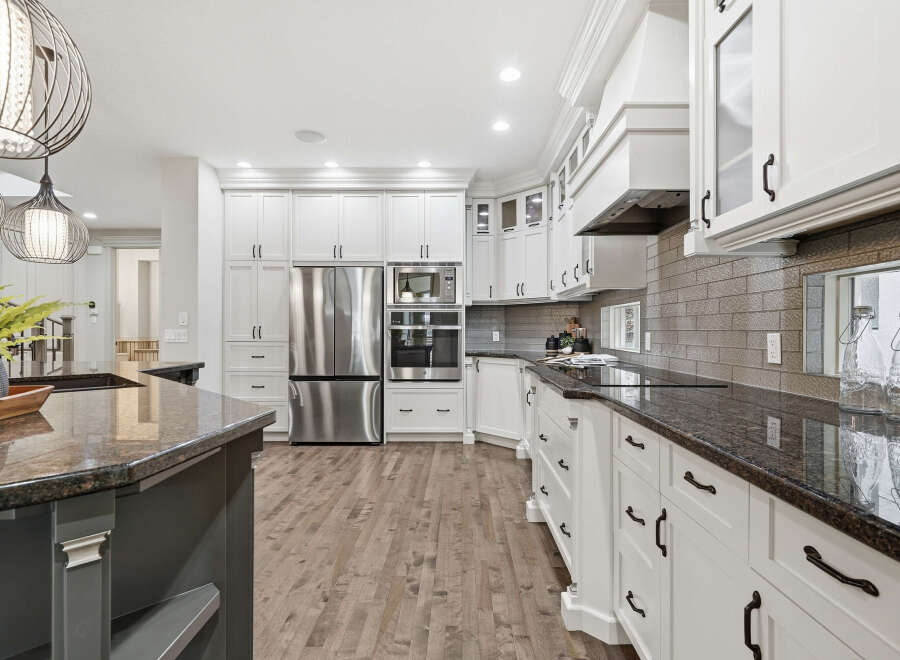 Experience luxury in this stunning modern kitchen, featuring sleek white cabinetry, granite countertops, and a full suite of stainless steel appliances.