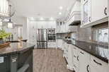 Experience luxury in this stunning modern kitchen, featuring sleek white cabinetry, granite countertops, and a full suite of stainless steel appliances.