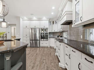 Experience luxury in this stunning modern kitchen, featuring sleek white cabinetry, granite countertops, and a full suite of stainless steel appliances.