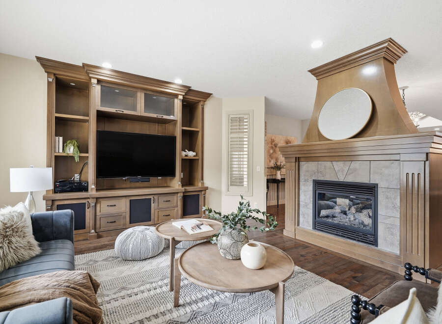 Experience luxury living in this stunning living room, featuring a grand wooden entertainment center and a cozy gas fireplace.