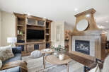 Experience luxury living in this stunning living room, featuring a grand wooden entertainment center and a cozy gas fireplace.