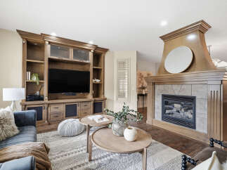 Experience luxury living in this stunning living room, featuring a grand wooden entertainment center and a cozy gas fireplace.