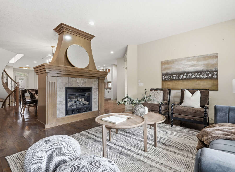 Step into this inviting living space featuring a grand wooden fireplace as the centerpiece, perfect for cozy evenings.