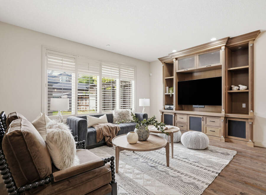 Step into this inviting living room, featuring a plush grey sofa adorned with cozy throws and decorative pillows, perfect for relaxation.