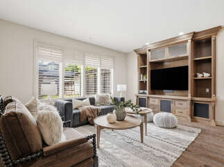 Step into this inviting living room, featuring a plush grey sofa adorned with cozy throws and decorative pillows, perfect for relaxation.