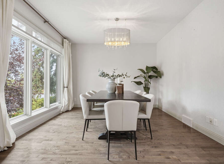 This elegant dining room features a large dark wood dining table surrounded by plush white upholstered chairs, perfect for hosting gatherings.