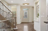 Step into this elegant entryway featuring a grand staircase with a wrought-iron railing and a beautiful stained-glass front door.