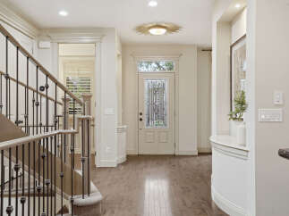 Step into this elegant entryway featuring a grand staircase with a wrought-iron railing and a beautiful stained-glass front door.