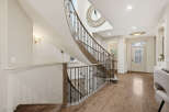 Step into a grand foyer featuring a stunning curved staircase with ornate railings and a decorative mirror accent.