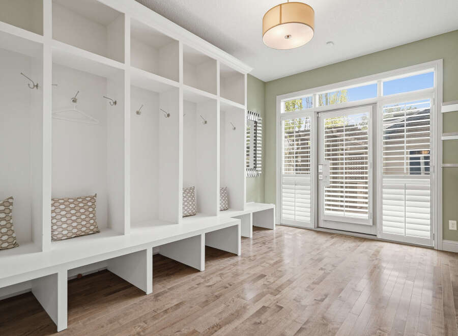 Step into this charming mudroom, featuring a built-in white shelving unit with multiple cubbies and coat hooks, perfect for organizing outerwear.