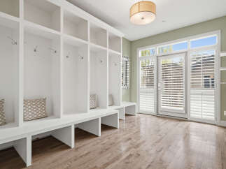 Step into this charming mudroom, featuring a built-in white shelving unit with multiple cubbies and coat hooks, perfect for organizing outerwear.