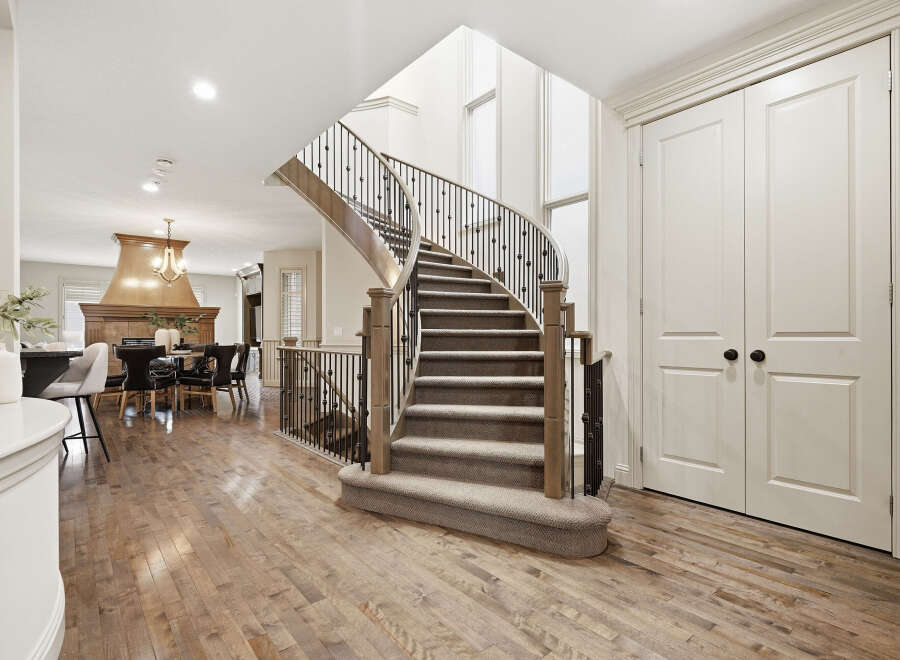 Step into this stunning home featuring a grand curved staircase with elegant wrought-iron railings, perfect for making a statement.