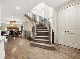 Step into this stunning home featuring a grand curved staircase with elegant wrought-iron railings, perfect for making a statement.
