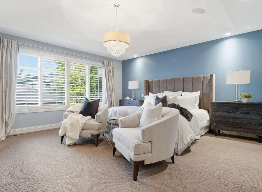 Experience luxury in this master suite, featuring a plush king-sized bed with a tall, upholstered headboard and crisp white linens.