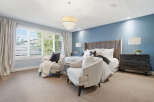 Experience luxury in this master suite, featuring a plush king-sized bed with a tall, upholstered headboard and crisp white linens.
