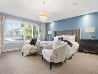 Experience luxury in this master suite, featuring a plush king-sized bed with a tall, upholstered headboard and crisp white linens.