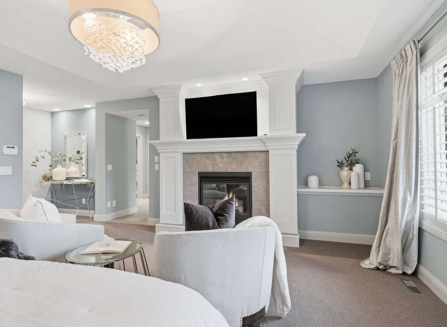 Experience luxury living in this beautifully appointed living room, featuring a grand fireplace as the centerpiece and a large television for entertainment.