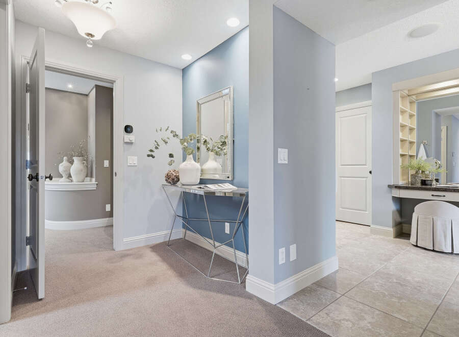 Step into this elegant hallway featuring a striking blue accent wall adorned with a decorative mirror and console table.