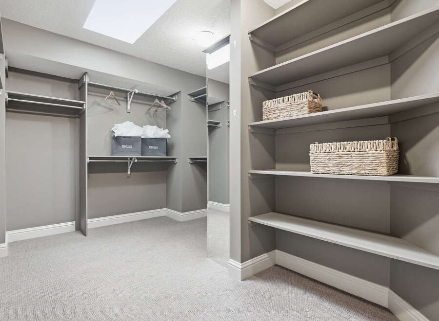 Discover ample storage in this spacious walk-in closet, featuring built-in shelving and multiple hanging rods.