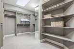 Discover ample storage in this spacious walk-in closet, featuring built-in shelving and multiple hanging rods.