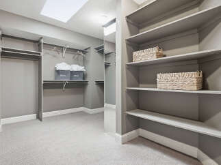 Discover ample storage in this spacious walk-in closet, featuring built-in shelving and multiple hanging rods.