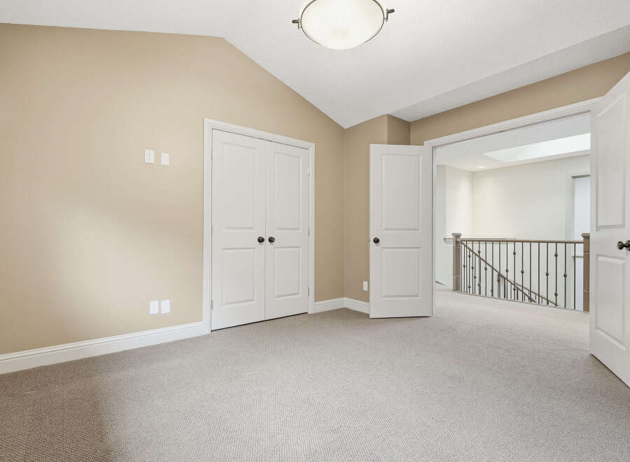 This spacious room features a vaulted ceiling with a central light fixture and neutral-toned walls, creating an airy and inviting atmosphere.