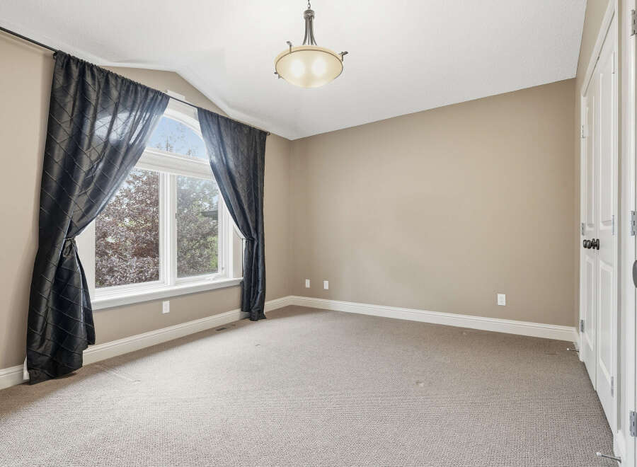This spacious room features a large arched window with elegant dark curtains, allowing natural light to fill the space.