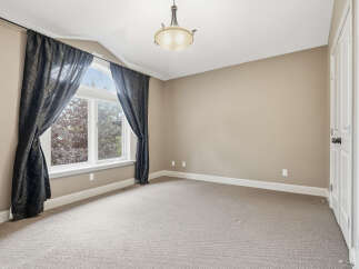 This spacious room features a large arched window with elegant dark curtains, allowing natural light to fill the space.