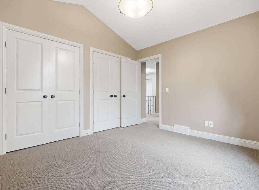 Discover this charming room featuring a vaulted ceiling and ample closet space with double doors.