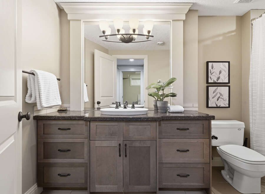 This bathroom features a spacious vanity with ample storage and a granite countertop, complemented by a modern vessel sink and elegant fixtures.